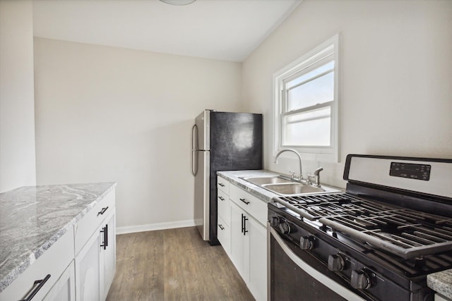 kitchen with dark hardwood / wood-style floors, light stone counters, white cabinetry, and appliances with stainless steel finishes