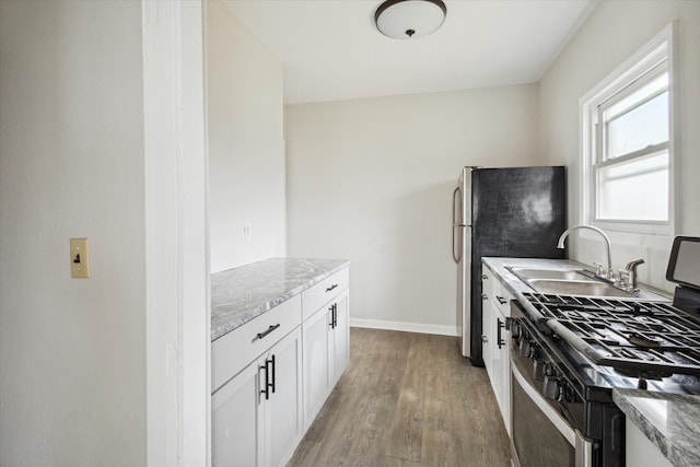 kitchen featuring light stone countertops, sink, stainless steel appliances, and light hardwood / wood-style floors