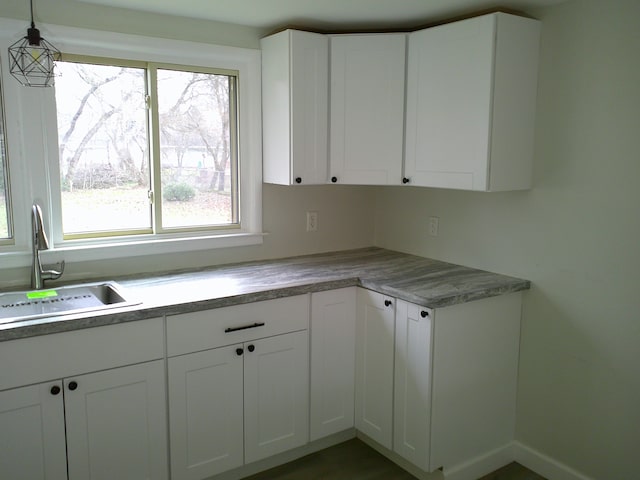 kitchen featuring white cabinetry, sink, and hanging light fixtures