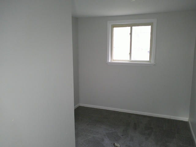 unfurnished room featuring dark carpet