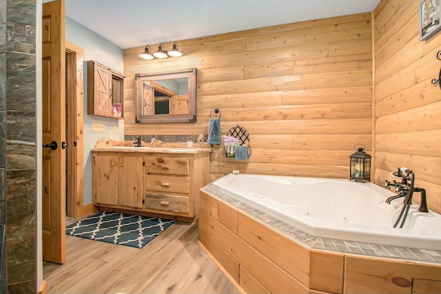 bathroom with a bath, hardwood / wood-style floors, vanity, and wood walls