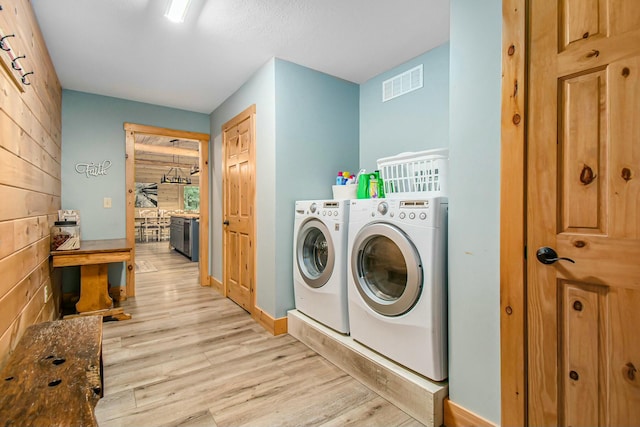 clothes washing area with washer and dryer and light wood-type flooring