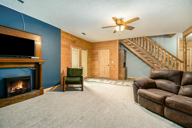 living room featuring carpet, ceiling fan, and wood walls