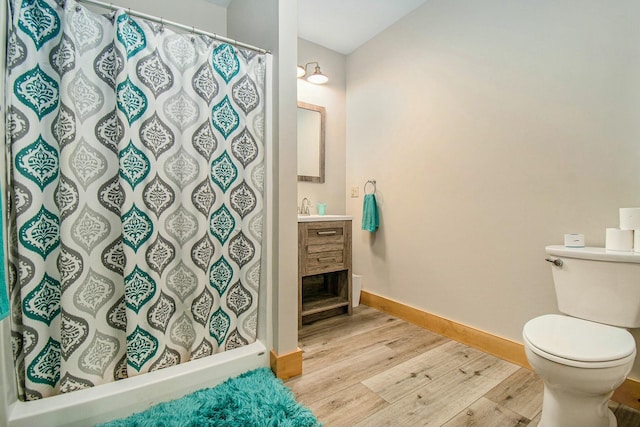 bathroom featuring walk in shower, toilet, vanity, and hardwood / wood-style flooring