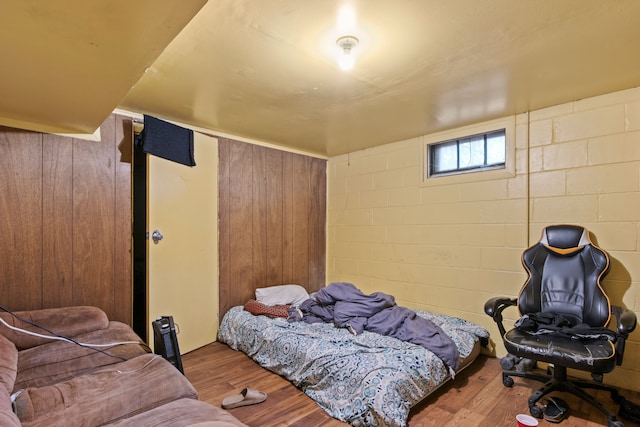 bedroom with hardwood / wood-style floors and wooden walls