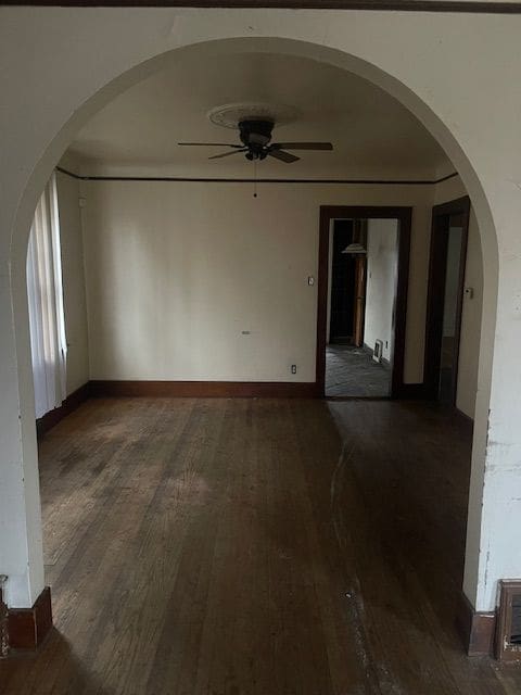 empty room with dark hardwood / wood-style floors and ceiling fan