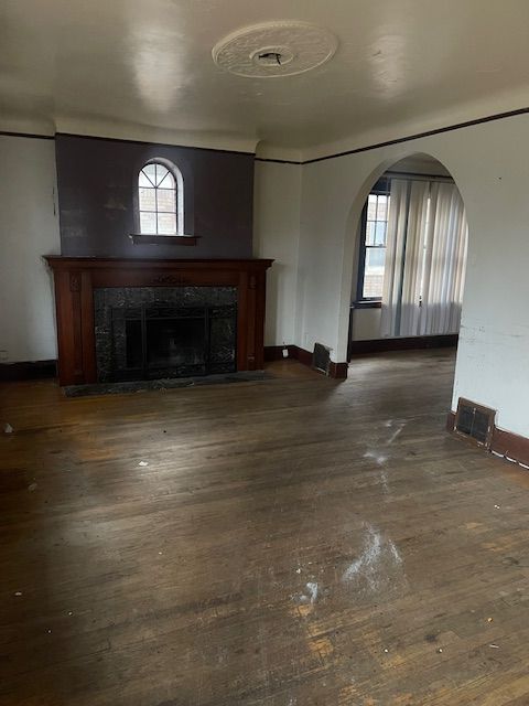 unfurnished living room with a fireplace, a healthy amount of sunlight, and dark hardwood / wood-style floors