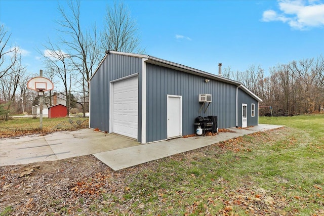 view of outdoor structure with an AC wall unit, a yard, and a garage