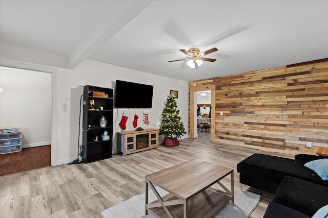 living room featuring ceiling fan, wood walls, and light hardwood / wood-style floors