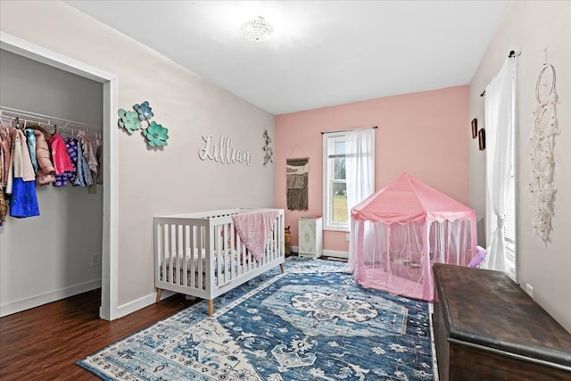 bedroom featuring dark hardwood / wood-style floors, a crib, and a closet