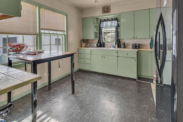 kitchen with green cabinets and black fridge