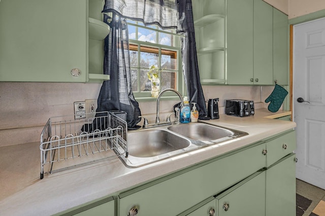 kitchen with decorative backsplash, green cabinets, and sink