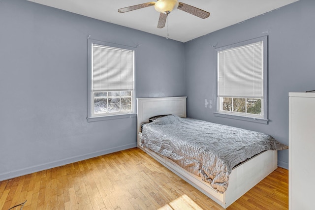 bedroom featuring ceiling fan, light wood-type flooring, and multiple windows