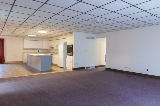 kitchen with stainless steel oven, a kitchen island, white fridge, light carpet, and white cabinets