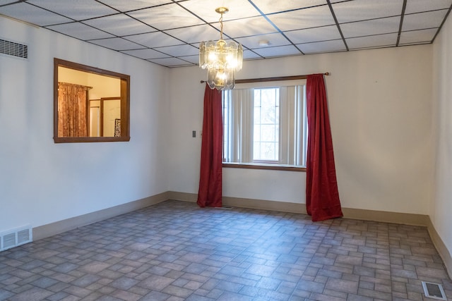 spare room featuring a paneled ceiling and an inviting chandelier