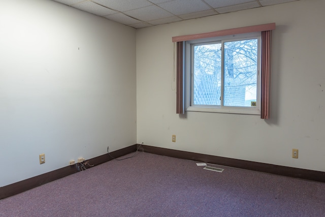 carpeted empty room featuring a paneled ceiling