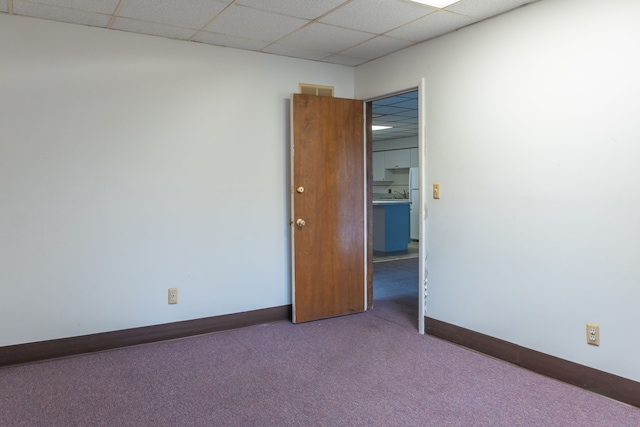 carpeted empty room featuring a paneled ceiling