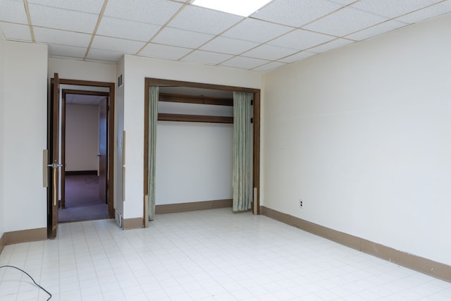 unfurnished bedroom with a closet and a drop ceiling