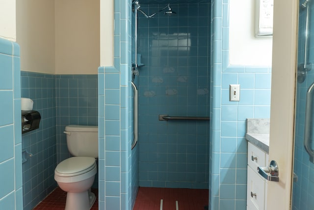 bathroom featuring a tile shower, vanity, toilet, and tile walls