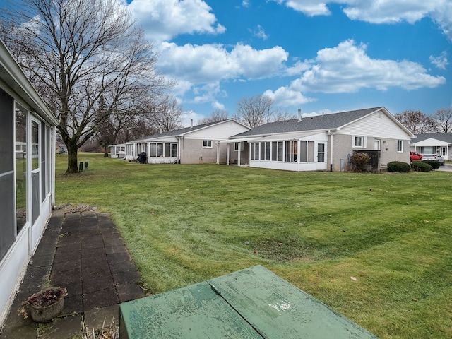 rear view of property featuring a lawn and a sunroom