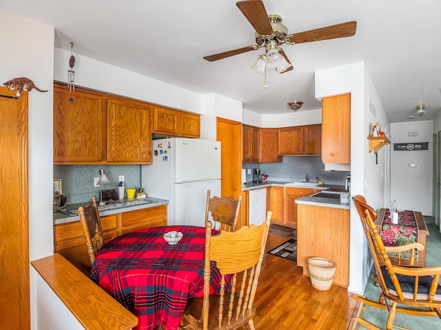 kitchen with backsplash, hardwood / wood-style floors, white appliances, and sink