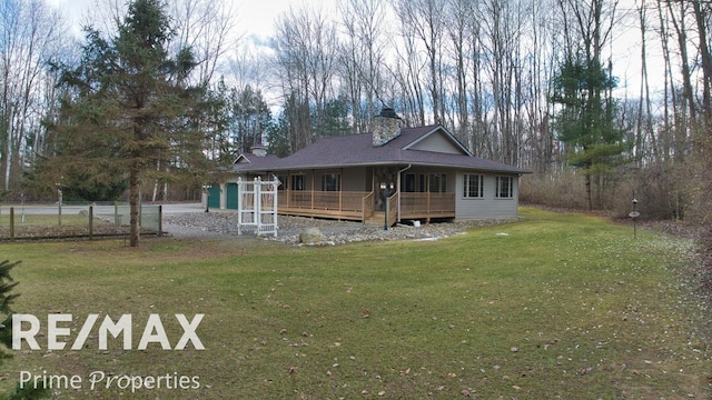 country-style home with a wooden deck, a chimney, a front lawn, and fence