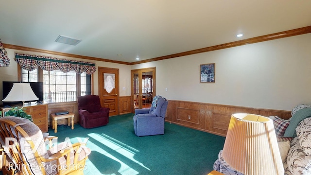 living area featuring a wainscoted wall, crown molding, visible vents, and carpet floors