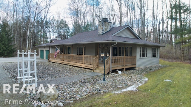 view of front of house featuring a front yard, roof with shingles, a chimney, driveway, and an attached garage