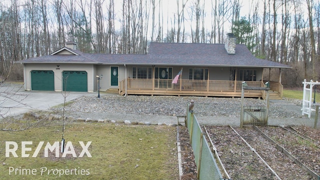 view of front facade featuring a porch, concrete driveway, roof with shingles, a chimney, and a garage