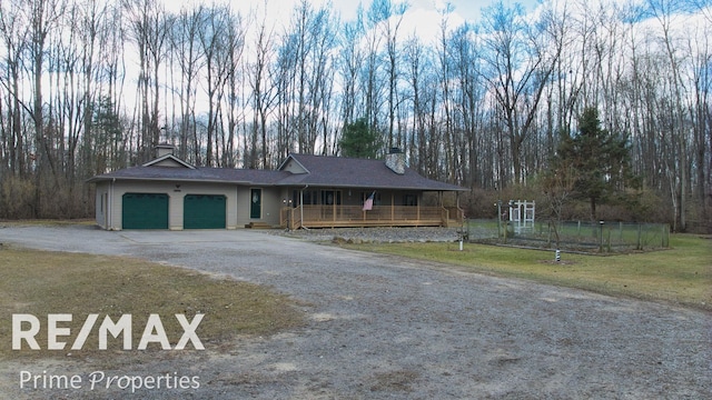 view of front facade with driveway, a porch, a front yard, an attached garage, and a chimney