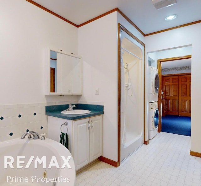 full bath with stacked washer / dryer, a shower stall, tile patterned floors, ornamental molding, and a bath