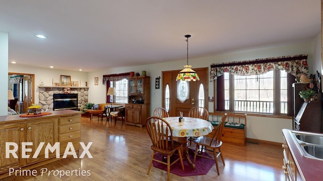 dining space with recessed lighting, a fireplace, baseboards, and light wood finished floors