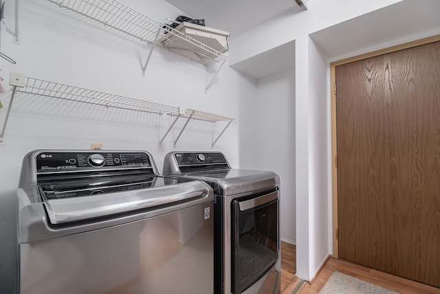 laundry area with light wood-type flooring and washing machine and dryer