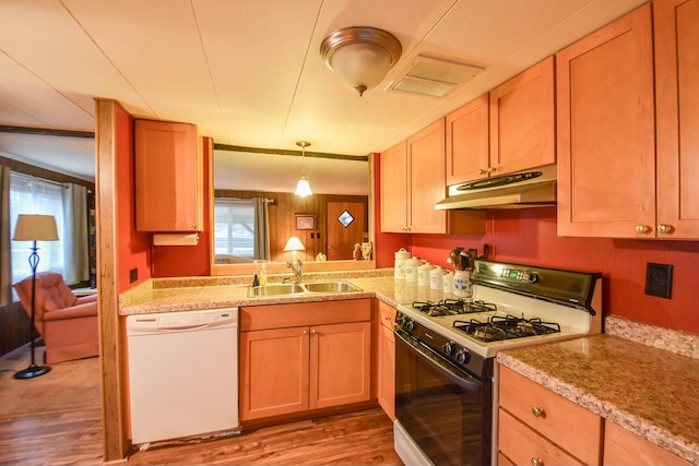 kitchen with pendant lighting, white appliances, sink, light wood-type flooring, and kitchen peninsula