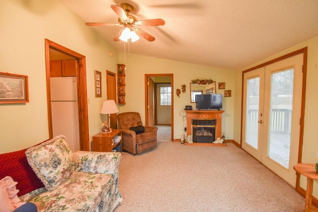 carpeted living room with french doors, a textured ceiling, vaulted ceiling, and ceiling fan