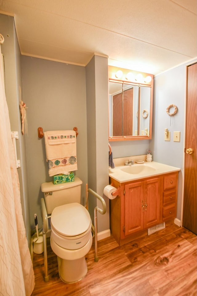 bathroom featuring wood-type flooring, vanity, toilet, and crown molding