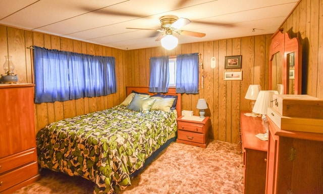 bedroom with carpet flooring, ceiling fan, and wood walls