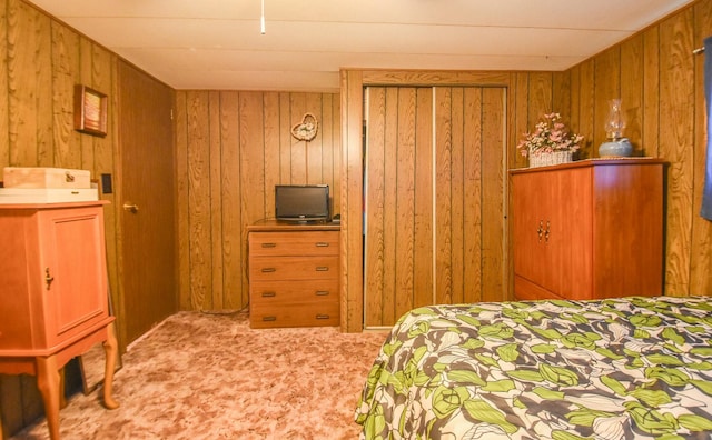 bedroom with light colored carpet and wood walls