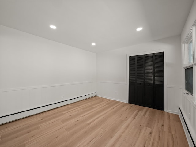 unfurnished room featuring a baseboard radiator and light hardwood / wood-style floors