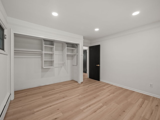 unfurnished bedroom featuring light hardwood / wood-style floors, crown molding, a baseboard radiator, and a closet