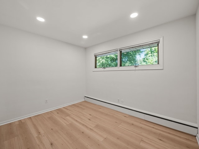 unfurnished room featuring light wood-type flooring and a baseboard heating unit