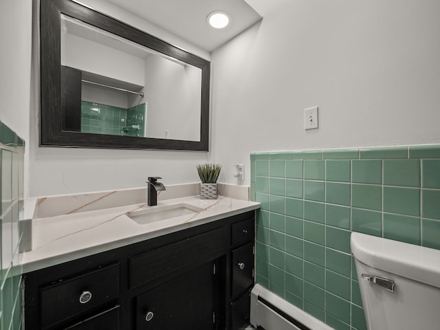 bathroom featuring a baseboard heating unit, vanity, tile walls, and toilet