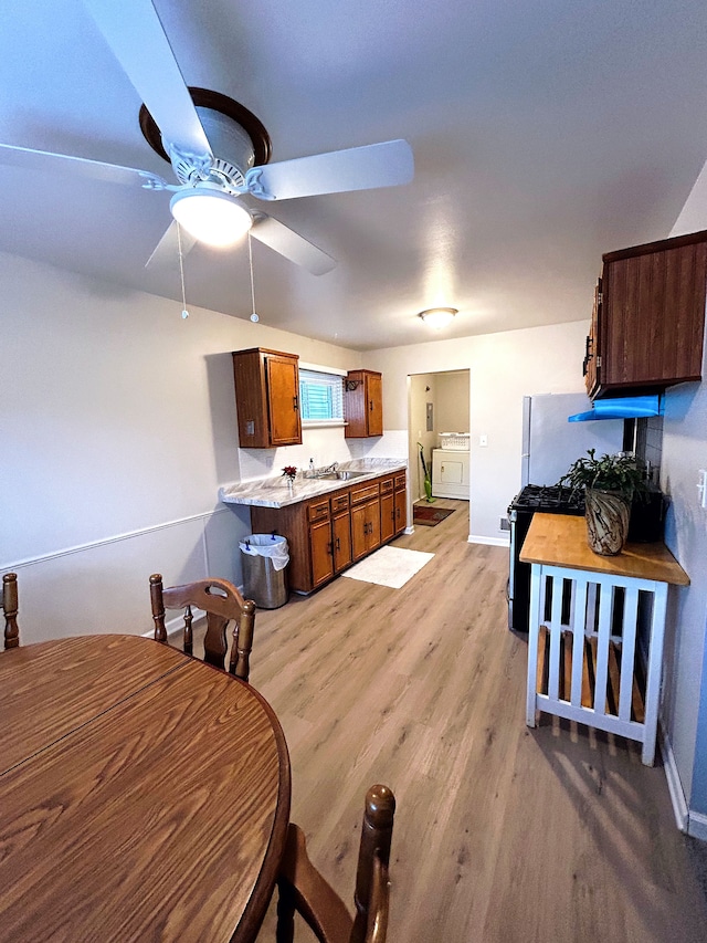 dining area with washing machine and dryer, light hardwood / wood-style flooring, ceiling fan, and sink