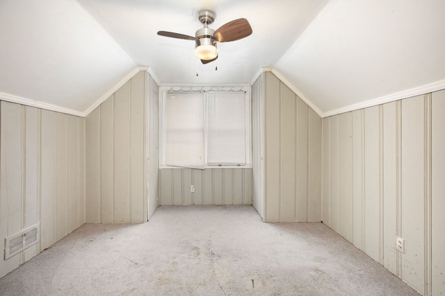 bonus room featuring light carpet, vaulted ceiling, ceiling fan, and wooden walls