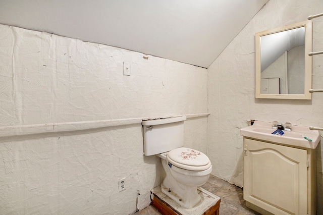 bathroom featuring vanity, toilet, and lofted ceiling