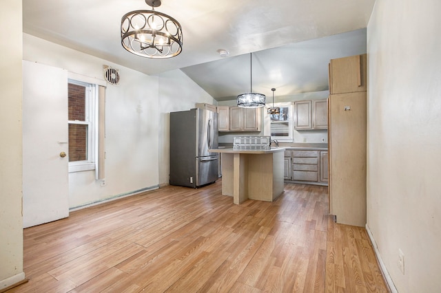 kitchen featuring stainless steel fridge, decorative light fixtures, a kitchen island, and light hardwood / wood-style floors