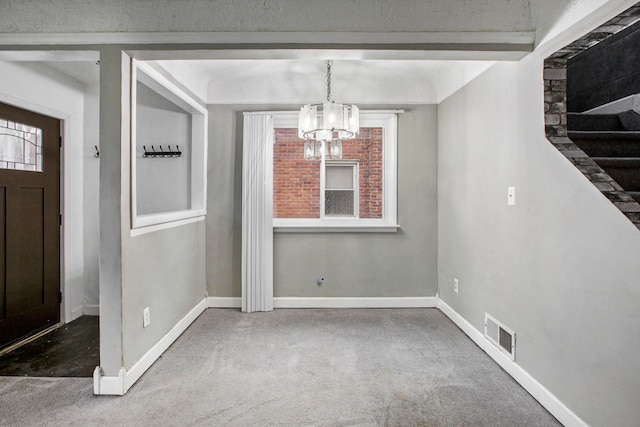 unfurnished dining area featuring carpet, a textured ceiling, and a notable chandelier