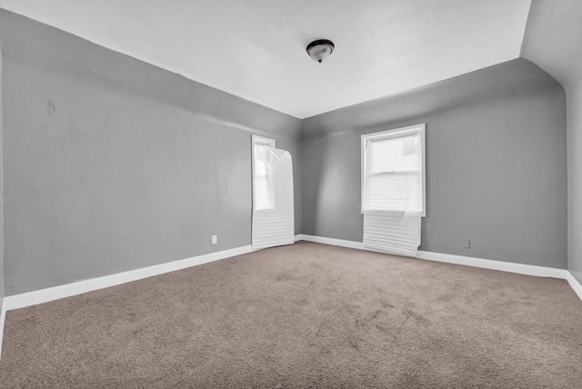 carpeted spare room featuring lofted ceiling