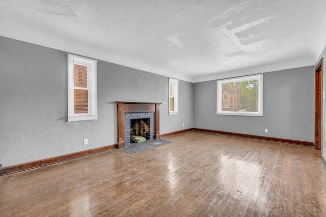 unfurnished living room featuring a fireplace, hardwood / wood-style floors, and a textured ceiling