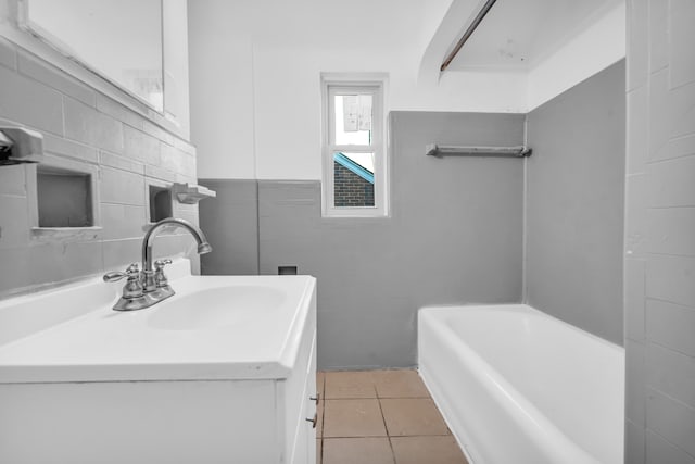 bathroom with a bath, vanity, tile patterned floors, and tile walls